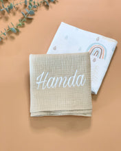 Load image into Gallery viewer, Muslin Swaddle plain and rainbow print on a flatlay
